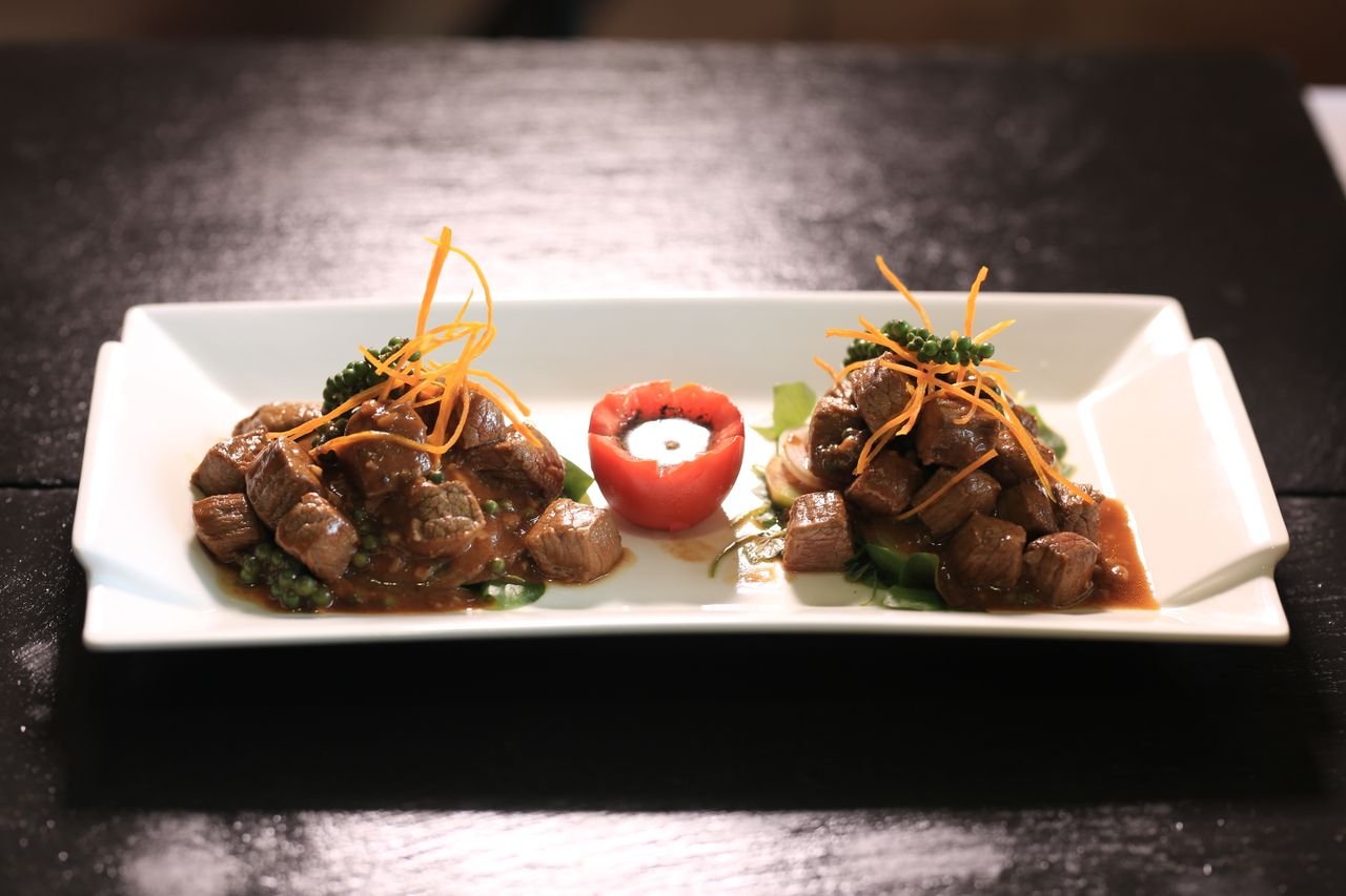 A beautifully presented beef dish in Phnom Penh, Cambodia, garnished with vegetables.