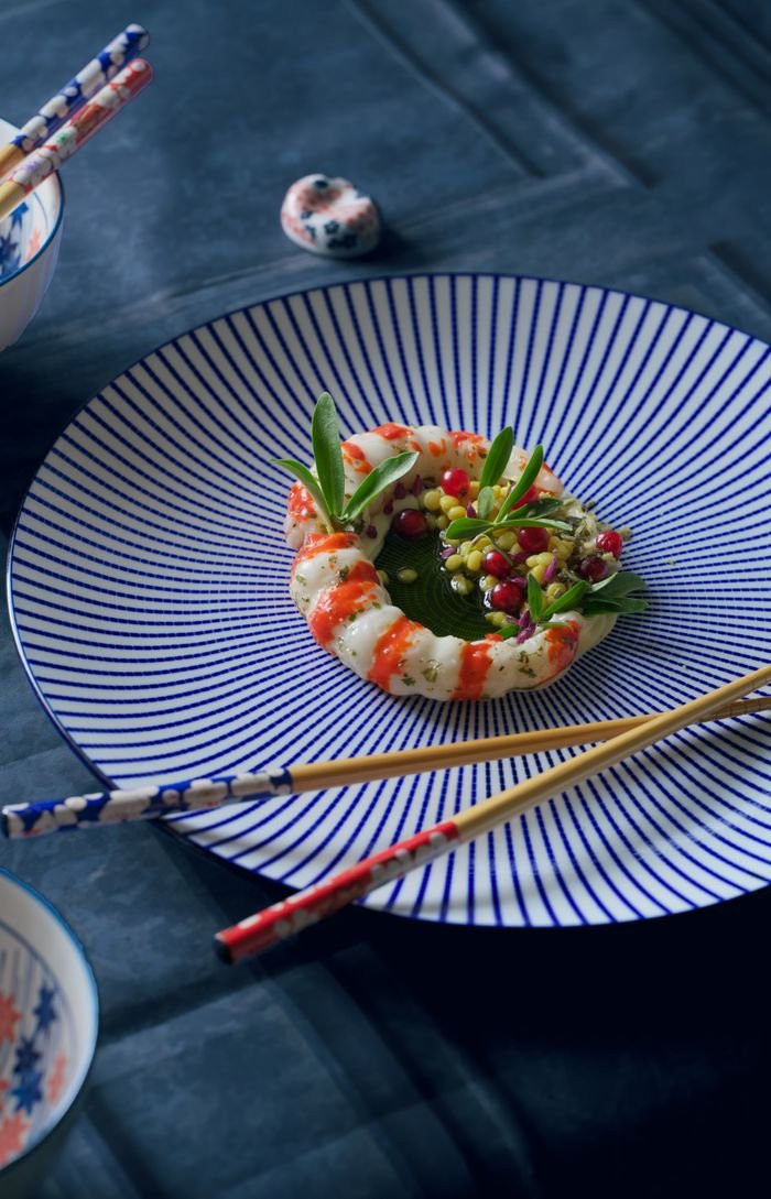 A beautifully plated gourmet dish on striped porcelain, garnished with fresh herbs, showcasing culinary artistry and elegance.