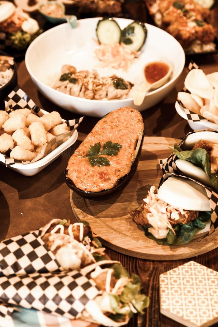 Assorted Asian fusion dishes with bao buns and appetizers displayed on a table.